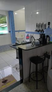 a kitchen with a counter and a stool in a room at COBERTURA Duplex com vista do Mar, Condomínio Village das ondas in Piúma