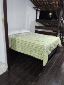 een bed met een groen dekbed in een kamer bij Aconchegante Casa Rústica ao lado da Praia in Santa Cruz Cabrália