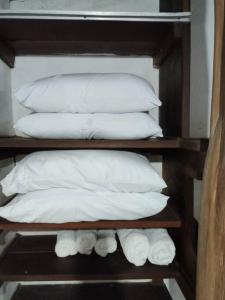 a group of white pillows on a wooden shelf at Aconchegante Casa Rústica ao lado da Praia in Santa Cruz Cabrália