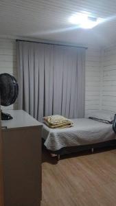 ein kleines Zimmer mit einem Bett und einem Vorhang in der Unterkunft Aconchegante casinha de madeira in Itapema