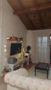 een woonkamer met een witte bank en een televisie bij Aconchegante casinha de madeira in Itapema