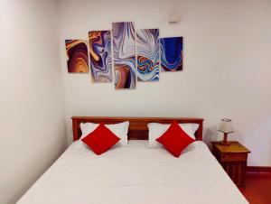 um quarto com uma cama com duas almofadas vermelhas em Araliya Uyana Residencies Colombo - Entire House with Two Bedrooms em Colombo