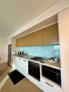 uma cozinha com um fogão e um frigorífico em Sea Pearl Apartment at Waterfront em Darwin