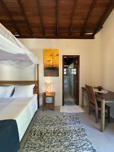 a bedroom with a bed and a table and a desk at Pousada Santo Mar in Arraial d'Ajuda