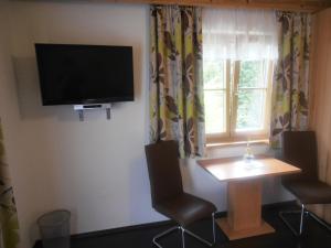 een kamer met een tafel en een televisie aan de muur bij Bauernhof Bachgut in Mühlbach am Hochkönig