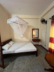 Schlafzimmer mit einem Bett mit Moskitonetz in der Unterkunft Saga Home in Ambalangoda