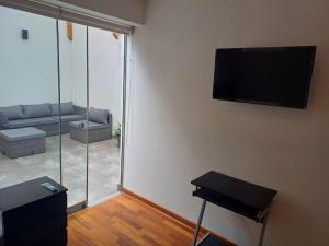 sala de estar con sofá y TV en la pared en Habitación acogedora Aramburú, en Lima