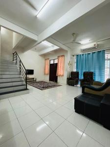 uma sala de estar com um sofá, cadeiras e escadas em Noor Homestay Giant em Kangar