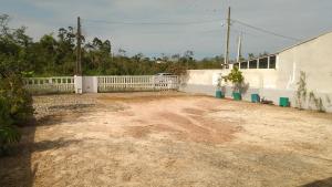 a dirt yard with a white fence and a building at Casa em Itapoá o Paraiso - Wifi - Ótimo Preço - Promoções in Itapoa