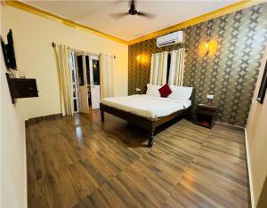 um quarto com uma cama e piso em madeira em Hotel Romeo's Place Near Baga Beach - 50 meters from Baga Beach em Baga
