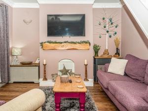 un soggiorno con divano viola e tavolo di Camoor Cottage a Hornsea
