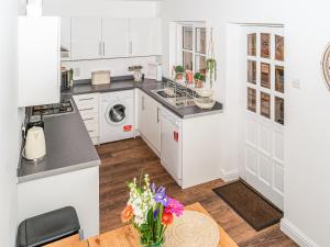 una cucina con armadi bianchi e un tavolo con fiori di Camoor Cottage a Hornsea