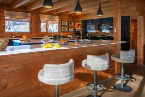 una cocina con una barra con tres taburetes en Chalet Temaïa - OVO Network, en La Toussuire