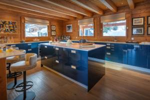 una gran cocina con armarios azules y un bar en Chalet Temaïa - OVO Network, en La Toussuire 23 fotos más