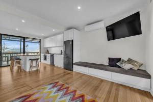 a large white kitchen with a bench with a flat screen tv at The Woodpecker in Merimbula