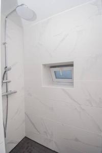 La salle de bains blanche est pourvue d'une douche et d'une fenêtre. dans l'établissement T2 Specialtravailleursfamillesetudiants, à Mâcon