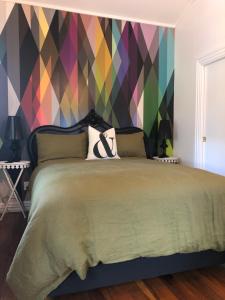 a bedroom with a bed with a colorful wall at Matamata Historic Cottage- The Wash-House in Matamata