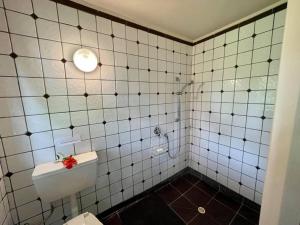 a white tiled bathroom with a toilet and a sink at Tapunui Spacious Retreat with Superfast Internet in Arorangi
