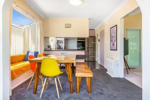 a kitchen and living room with a wooden table and chairs at Retro 4 bedroom home, warm and welcoming, quiet location in Porirua