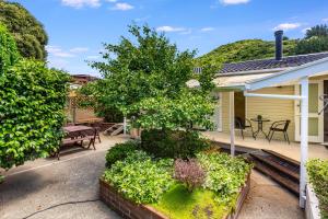 a backyard of a house with a tree and a bench at Retro 4 bedroom home, warm and welcoming, quiet location in Porirua