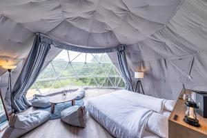 - une chambre dans une tente avec un lit et une table dans l'établissement THE GLAMPING PLAZA 伊勢志摩BASE, à Ugata