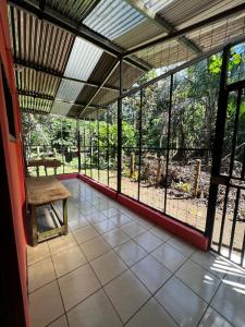 un porche cubierto con un banco en el suelo de baldosa en Paraíso Verde en Siquirres