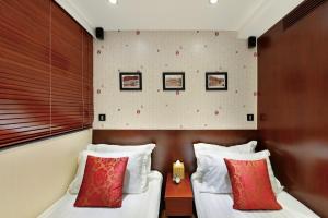 2 łóżka w pokoju hotelowym z białymi i czerwonymi poduszkami w obiekcie The Shai Red - formerly Mingle in The Shai w Hongkongu