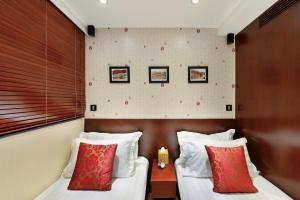 two beds in a hotel room with red and white pillows at The Shai Red - formerly Mingle in The Shai in Hong Kong