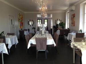 a dining room with white tables and chairs and a chandelier at Hotel La Cigale in La Croix-Valmer