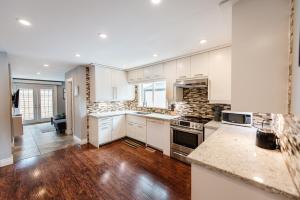 eine Küche mit weißen Schränken und Holzböden in der Unterkunft Home away from home, 5bdr, fastwifi, spacious home in Hamilton