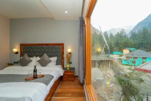 a room with two beds and a large window at Kasol ArtHouse - The Treasure of Himalayas in Kasol