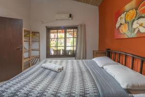 een slaapkamer met een groot bed met een oranje muur bij Pousada Refúgio do Rosa in Praia do Rosa