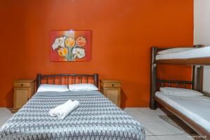 een slaapkamer met 2 stapelbedden en een oranje muur bij Pousada Refúgio do Rosa in Praia do Rosa