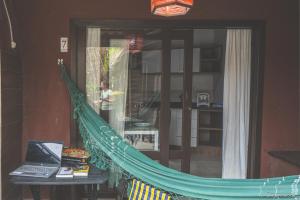 een hangmat in een kamer met een laptop op een tafel bij Pousada Refúgio do Rosa in Praia do Rosa