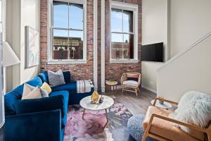 a living room with a blue couch and a brick wall at Trendy 3 bedroom Loft in Chinatown with Parking! in Victoria