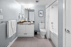 La salle de bains blanche est pourvue d'un lavabo et de toilettes. dans l'établissement Trendy 3 bedroom Loft in Chinatown with Parking!, à Victoria