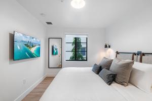 a white bedroom with a large white bed and two windows at Lux Retreat By Renzzi in Miami