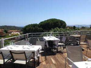 a restaurant with tables and chairs on a balcony at Hotel La Cigale in La Croix-Valmer