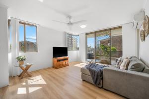 a living room with a couch and a flat screen tv at Sundial 202 8-10 Hollingworth Street in Port Macquarie