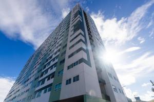 un edificio alto y blanco con el sol en el cielo en Meu aconchego em Maceió - 2qts com ar e 1 vaga de garagem, en Maceió