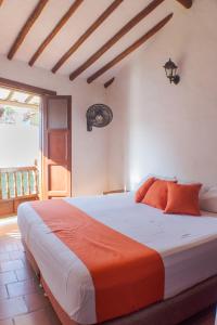 um quarto com uma cama grande e um cobertor laranja em El Retiro Barichara 206 em Barichara