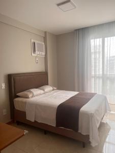 a bedroom with a large bed and a window at ESPETACULAR!! Apto na PRAIA DE ITAPARICA - Com Wi-Fi 360mbps, Ar Condicionado, Estacionamento, Globoplay e Cozinha Completa in Vila Velha