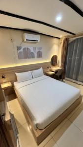 a bedroom with a large white bed and a window at La Berza Resort in Subang