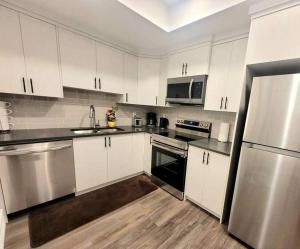 a kitchen with white cabinets and stainless steel appliances at Somy Suite - Cozy 2bedrom with two queens bed and free street parking in Calgary