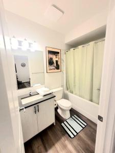 a white bathroom with a toilet and a sink at Somy Suite - Cozy 2bedrom with two queens bed and free street parking in Calgary