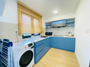 a kitchen with blue cabinets and a washer at Sunway Grid Cosmo Suite WI-FI 6pax BigBOX Legoland in Kampong Pendas