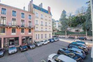 ein Parkplatz mit Autos vor den Gebäuden in der Unterkunft Ma Pref de Miss K in Mâcon