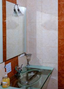 ein Badezimmer mit einem Glaswaschbecken und einem Spiegel in der Unterkunft Hostal Café Racer in Jardin
