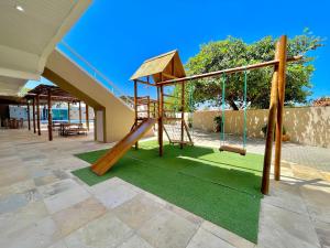 a playground with a slide on a green lawn at Pousada Beach House Dunas in Beberibe