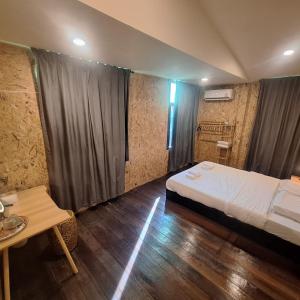 a bedroom with a bed and a table in a room at SUNZI BOUTIQUE HOSTEL : ซันซิ บูทีค โฮสเทล in Betong